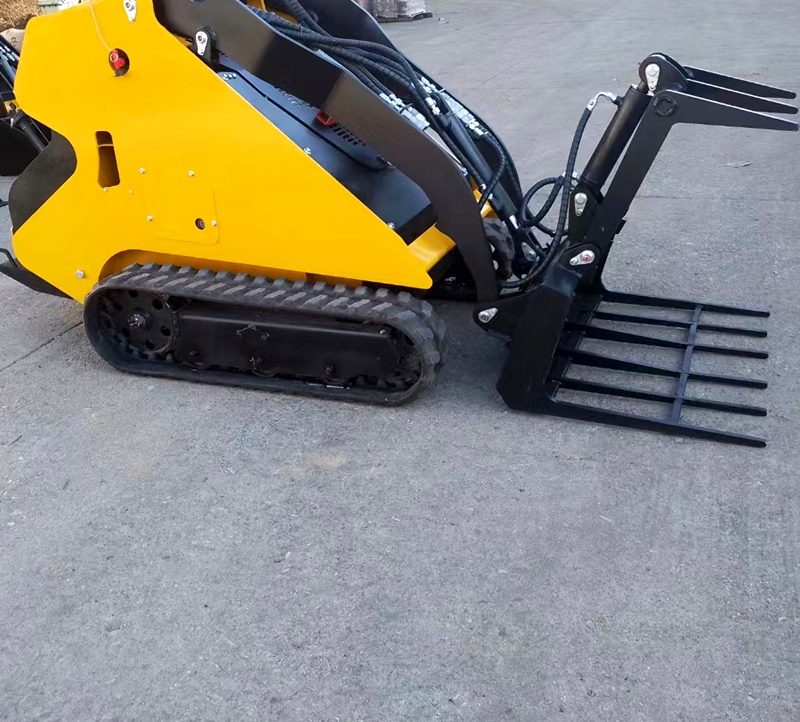 Mini tracked skid steer loader with pallet forks installed